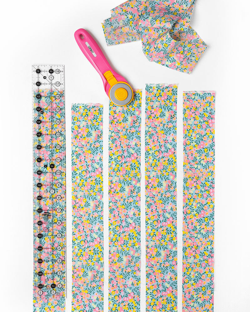 Pieces of quilt binding and a ruler on a white background.