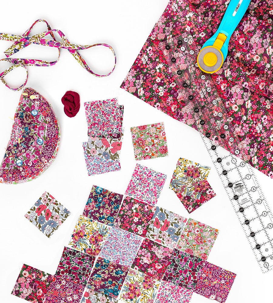 Red fabric charm squares and a ruler on a white background.